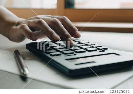 Black calculator in the hands of a woman doing calculations Black calculator in the hands of a woman doing calculations 128125021