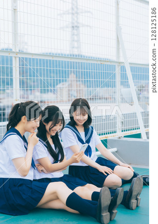 一個高中女生在屋頂上看智能手機 128125186