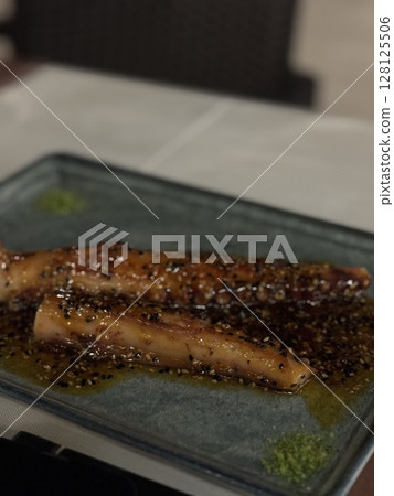 Delicious grilled meat garnished with herbs, served on a black ceramic plate, ideal for food, restaurant, and culinary content. Delicious grilled meat garnished with herbs, served on a black ceramic plate, ideal for food, restaurant, and culinary content. 128125506