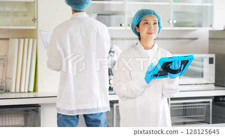 身穿衛生白大褂的男女工作人員正在檢查廚房 128125645