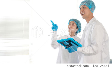 Male and female workers in sanitary white coats checking the warehouse 128125651