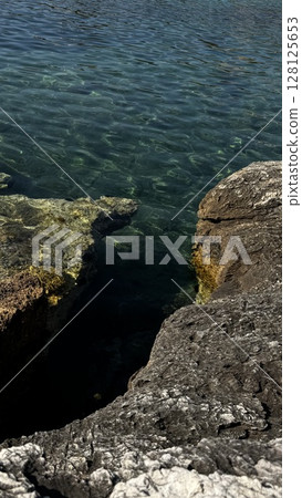 Sunlit Rocks Beneath Clear Blue Sea Water Sunlit Rocks Beneath Clear Blue Sea Water 128125653