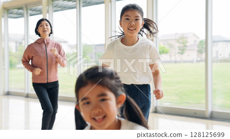 A girl and a female teacher running in the gym A girl and a female teacher running in the gym 128125699