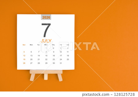 Calendar page for July 2026 with wood easel on orange color background. 128125728