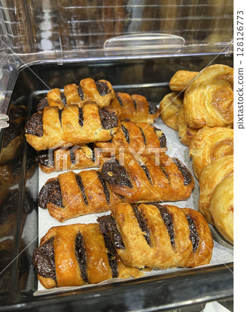 Photographing neatly arranged cinnamon rolls and chocolate danishes in a cafeteria Photographing neatly arranged cinnamon rolls and chocolate danishes in a cafeteria 128126773
