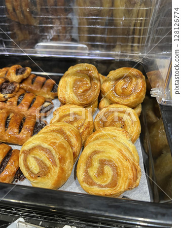 Photographing neatly arranged cinnamon rolls and chocolate danishes in a cafeteria 128126774