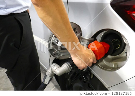 Male office worker refueling a car with gasoline 1 128127195