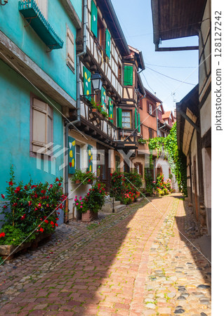 Street with picturesque colorful half-timbered houses in the medieval village of Eguisheim, Alsace, France. Village is ranked in the top 20 of Les Plus Beaux Villages de France. Alsace wine route 128127242
