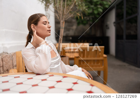 Woman Relaxation Garden: Pensive woman relaxes with closed eyes in outdoor cafe during sunny daytime. Woman Relaxation Garden: Pensive woman relaxes with closed eyes in outdoor cafe during sunny daytime. 128127269