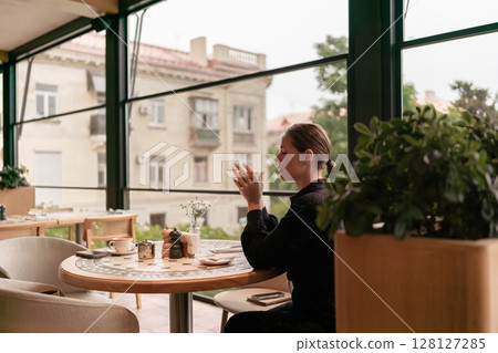 Cafe Woman Coffee: Lady sips beverage in restaurant by window on cloudy day for break. 128127285