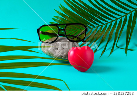 Trendy sunglasses on rock with palm leaves. 128127298