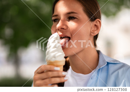 Icecream Woman Summer: Young woman enjoys icecream cone outside on a bright sunny day in summer. Icecream Woman Summer: Young woman enjoys icecream cone outside on a bright sunny day in summer. 128127308
