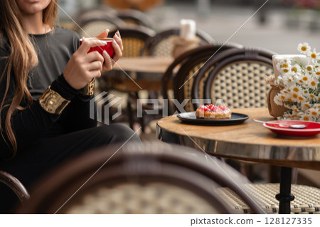 Cafe Coffee Donut, woman enjoys coffee and dessert outdoors in daytime for a relaxing break. Cafe Coffee Donut, woman enjoys coffee and dessert outdoors in daytime for a relaxing break. 128127335