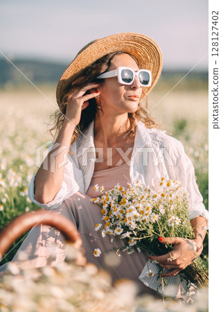 Daisies Woman Summer: Woman rests in daisy field during summer, holding flowers, seeking relaxation. 128127402
