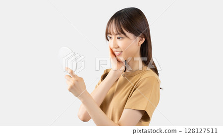 年輕女子在鏡子裡檢查自己的皮膚 年輕女子在鏡子裡檢查自己的皮膚 128127511