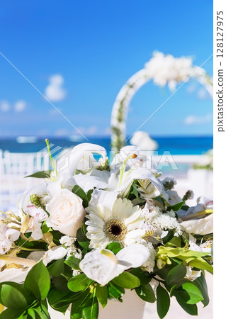 Bunch of flowers in a vase for wedding ceremony and beautiful wedding arch on a tropical beach 128127975