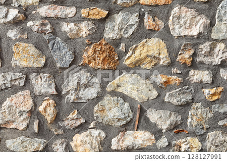 Old stone wall made of large gray natural stones. Stone wall rustic texture background. 128127991