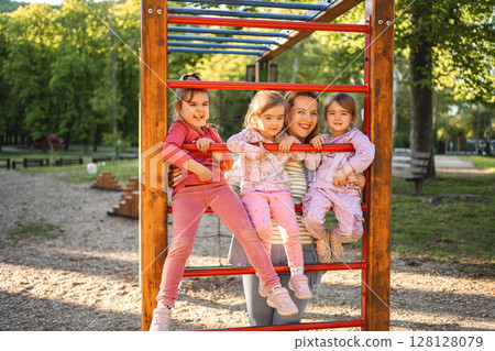 Smiling mom with daughters on the playground 128128079