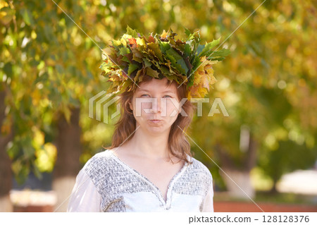 Caucasian young female with leaf crown in nature setting, green and yellow 128128376