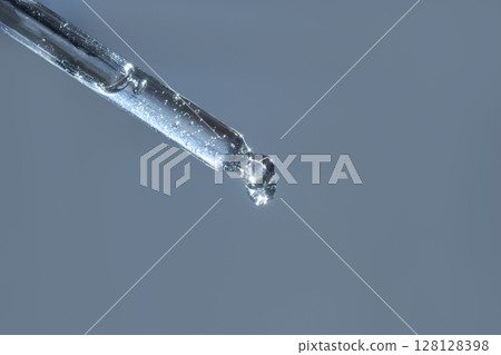 Close-up of transparent dropper with droplet on light blue background Close-up of transparent dropper with droplet on light blue background 128128398