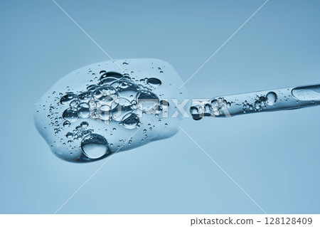 The texture of serum with spicules in a dropper on a blue background. 128128409