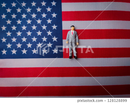 Miniature people stand on a us flag background. Geopolitical concept. Miniature people stand on a us flag background. Geopolitical concept. 128128899