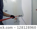 A man paints the inner wall of his house. Apartment renovation. Concrete walls are painted with a paint roller. High quality photo 128128960