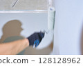 Close-up of a hand with a roller. Apartment renovation. Concrete walls are painted gray with a paint roller. High quality photo 128128962