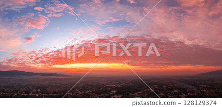 Aerial view of Clouds streak the sunlight above unban village. 128129374