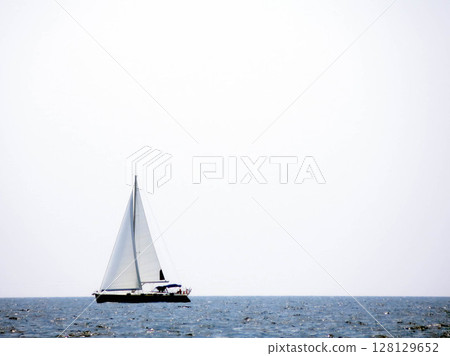 Sailing Yacht Gliding Across the Calm Sea Beneath a Clear Sky During Midday 128129652