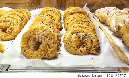 Freshly baked spiral pastries decorated with flax seeds on display at a bakery. Perfect for breakfast, brunch or a holiday treat. Freshly baked spiral pastries decorated with flax seeds on display at a bakery. Perfect for breakfast, brunch or a holiday treat. 128129737