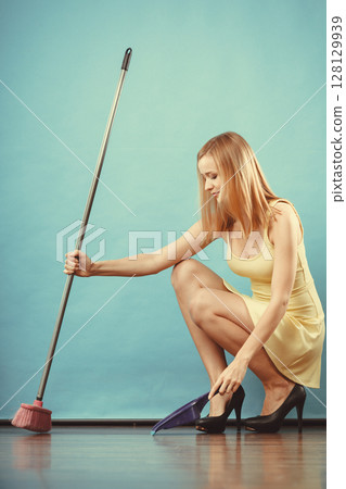 Elegant woman sweeping floor with broom Elegant woman sweeping floor with broom 128129939
