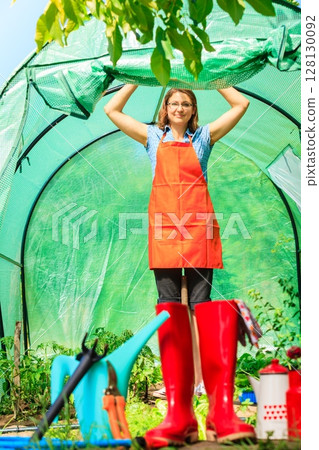 Female farmer and gardening tools in garden 128130092