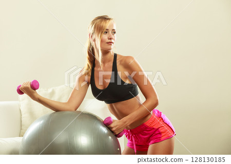 Woman with gym ball and dumbbell doing exercise Woman with gym ball and dumbbell doing exercise 128130185