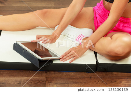 Fit woman sitting on floor with tablet pc Fit woman sitting on floor with tablet pc 128130189