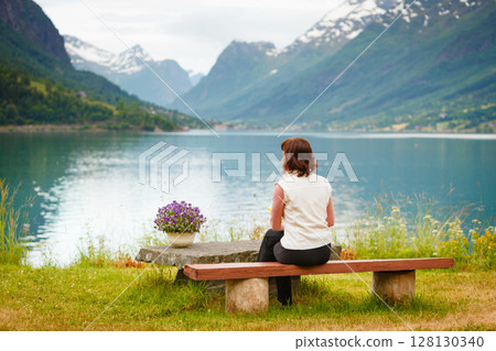 Woman tourist relaxing on fjord sea shore, Norway 128130340