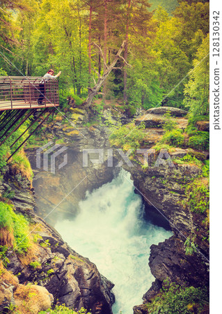 Tourist with camera on Gudbrandsjuvet waterfall, Norway 128130342