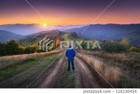 Man on the rural dirt road on the hill looking on mountain in fog 128130458