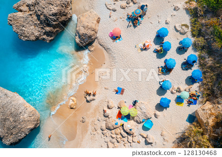 Aerial view of blue sea, beach with umbrellas, rocks in water Aerial view of blue sea, beach with umbrellas, rocks in water 128130468