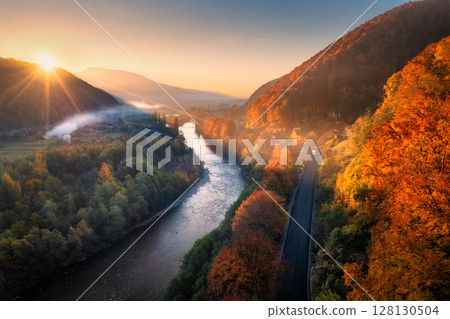 Aerial view of a winding river, road and vibrant autumn forest 128130504