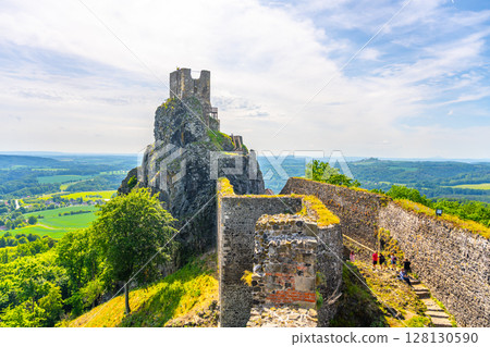 Visitors explore the majestic Baba Tower amidst the ancient Trosky Castle ruins. Set in Bohemian Paradise, the site offers stunning views of the surrounding landscape on a clear day. 128130590