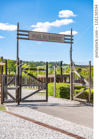 The entrance gate to the former Vojna prison complex in Lesetice, Czechia, features a rustic wooden structure and a sign, symbolizing a historical transition. 128130594