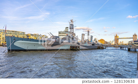 HMS Belfast, a historic warship, is docked in the River Thames. The ship is surrounded by city views, including the iconic Tower Bridge on a sunny afternoon. HMS Belfast, a historic warship, is docked in the River Thames. The ship is surrounded by city views, including the iconic Tower Bridge on a sunny afternoon. 128130638