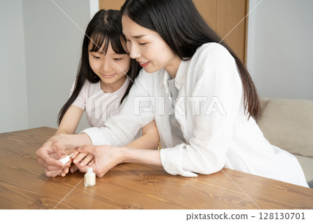 Mother applying nail polish to daughter's nails Mother applying nail polish to daughter's nails 128130701
