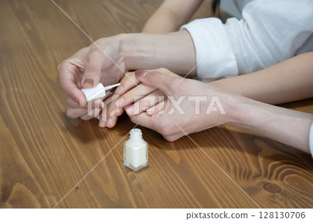 Mother applying nail polish to daughter's nails 128130706
