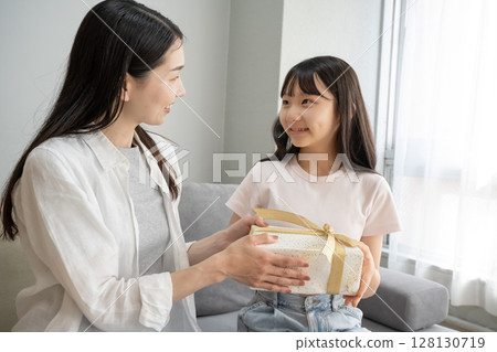 Mother giving presents to her daughter Mother giving presents to her daughter 128130719