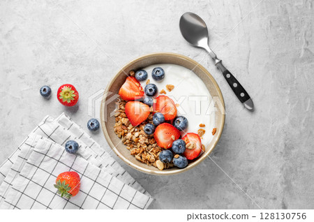 Natural yogurt with granola, blueberry and strawberry in a bowl on a light background Natural yogurt with granola, blueberry and strawberry in a bowl on a light background 128130756