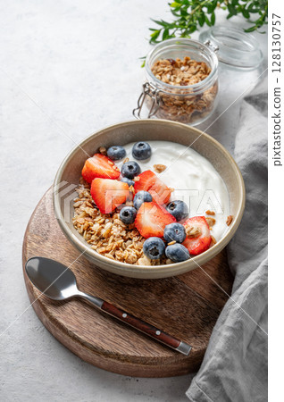 Natural yogurt with granola, blueberry and strawberry in a bowl on a light background Natural yogurt with granola, blueberry and strawberry in a bowl on a light background 128130757