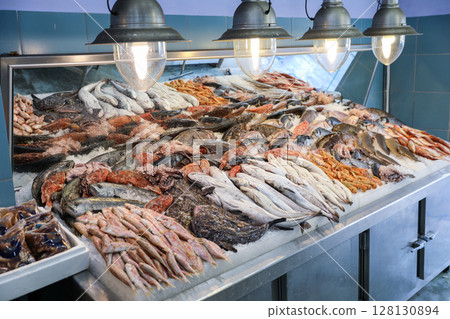 Fish market bustling with activity where vendors display fresh catch on ice. Shiny fishes, shellfish, and crustaceans create colorful array, highlighting local seafood culture in Greece. Fish market bustling with activity where vendors display fresh catch on ice. Shiny fishes, shellfish, and crustaceans create colorful array, highlighting local seafood culture in Greece. 128130894