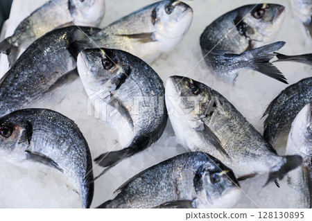 Fresh sea bass fishes on ice in Greek fish market. Horizontal. Daylight. Close. Fresh sea bass fishes on ice in Greek fish market. Horizontal. Daylight. Close. 128130895